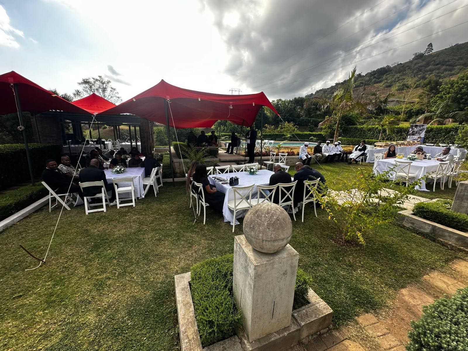 Outdoor memorial gathering under red gazebos